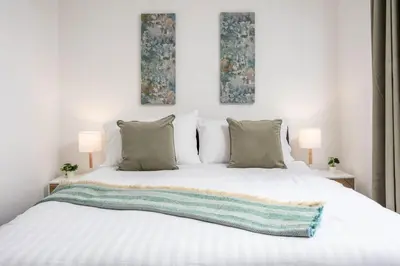 a bedroom with a white bed with two paintings on the wall at Elms Way No33 – Donnini Apartments in Ayr
