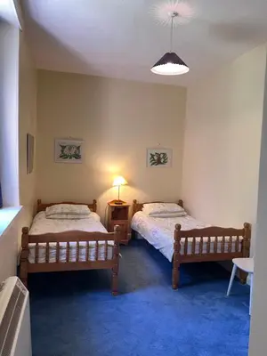 a bedroom with two beds and a lamp in it at Laundry Cottage in Lanark
