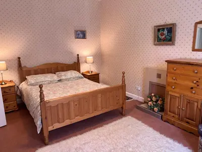 a bedroom with a wooden bed and two night stands at Laundry Cottage in Lanark