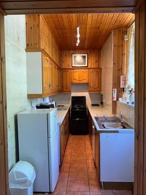 a kitchen with wooden cabinets and a white refrigerator at Laundry Cottage in Lanark
