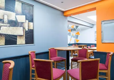a room with tables and chairs and a painting on the wall at Apartment 16 in Castle Douglas