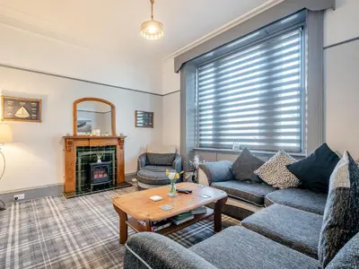 a living room with couches and a table and a fireplace at Harbour View House in Girvan