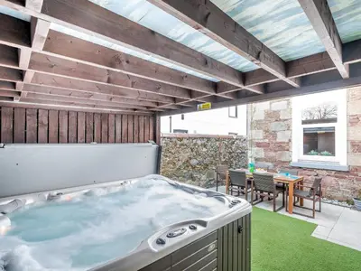 a hot tub in a patio with a table and chairs at Harbour View House in Girvan
