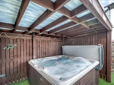 a jacuzzi tub in a backyard with a roof at Harbour View House in Girvan