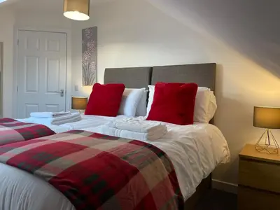 a bedroom with two beds with red pillows at The Old Stables 17a in Dumfries