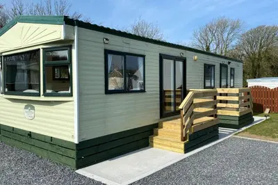 a green tiny house with a wooden deck at Caravan - Sleeps 4 - Pet friendly - Parking in Newton Stewart
