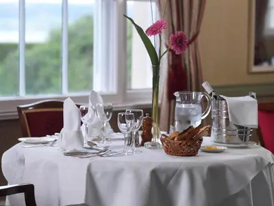 a white table with a vase with a pink flower on it at North West Castle Hotel in Stranraer