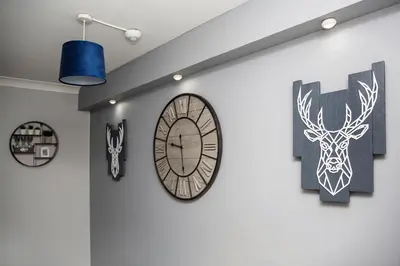 a clock on a wall with paintings and a blue light at St Andrews Guest House in Irvine