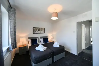a bedroom with a black bed with blue pillows at Mews House in Ayr