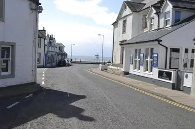 an empty street with buildings and the ocean in the background at Harbourside Apartments in Portpatrick