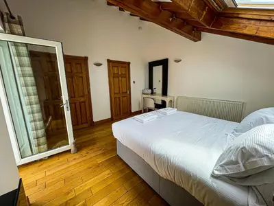 a bedroom with a white bed and wooden floors at Harbourside Apartments in Portpatrick