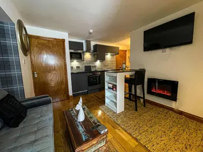 a living room with a kitchen with a fireplace at Harbourside Apartments in Portpatrick