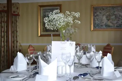 a table with wine glasses and a vase of flowers at Fernhill Hotel in Portpatrick