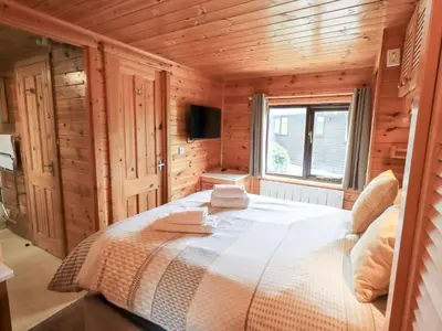 a bedroom with a bed in a wooden cabin at Squirrels Leap in Keswick