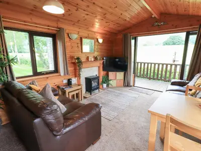 a living room with a leather couch and a fireplace at Squirrels Leap in Keswick