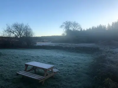 a picnic table in the middle of a field at Merrick Cottage in Bargrennan
