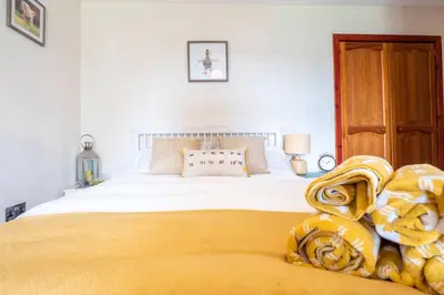 a bedroom with a large bed with a yellow blanket at Meadowhead Cottage, Traditional Scottish Cottage in Waterside