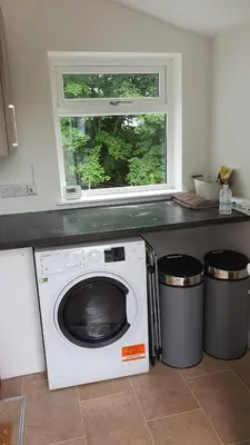 a washing machine in a kitchen with a window at Dairy Cottage with sea views in Girvan