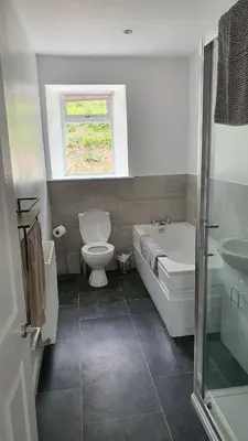 a bathroom with a toilet and a tub and a sink at Dairy Cottage with sea views in Girvan