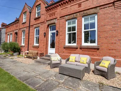 a group of chairs and tables in front of a brick building at Seascape in Annan