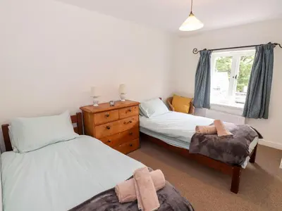 a bedroom with two beds and a dresser and a window at Two Town End in Penrith