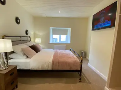 a bedroom with a bed and a television on a wall at Rattlebeck Farm Cottage and Hot Tub PET FRIENDLY in Welton