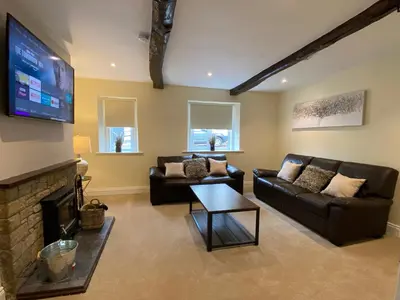 a living room with two couches and a flat screen tv at Rattlebeck Farm Cottage and Hot Tub PET FRIENDLY in Welton