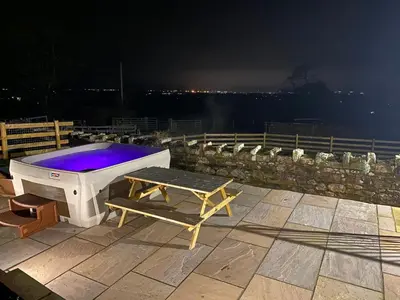 a hot tub sitting on a patio at night at Rattlebeck Farm Cottage and Hot Tub PET FRIENDLY in Welton