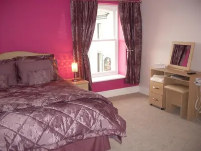 a bedroom with pink walls and a bed and a window at The Golden Lion Hotel in Maryport