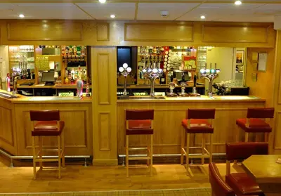 a bar in a restaurant with red stools at The Golden Lion Hotel in Maryport