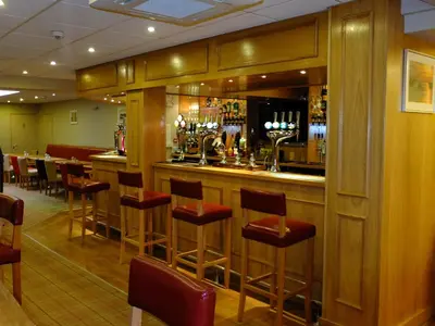 a bar in a restaurant with red stools at The Golden Lion Hotel in Maryport