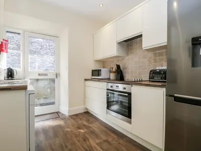 a kitchen with white cabinets and a stove top oven at The Bakers Loft in Ambleside