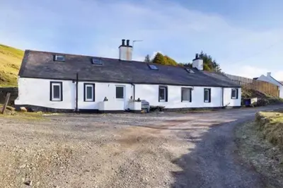 a white building with a black roof on a road at Glendyne Cottages, Highest Village in Scotland in Wanlockhead