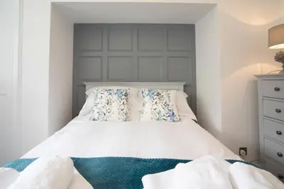 a bedroom with a white bed with blue and white pillows at Laundry Cottage: Drumlanrig Castle in Thornhill