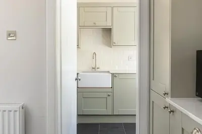 a kitchen with white cabinets and a sink at Laundry Cottage: Drumlanrig Castle in Thornhill