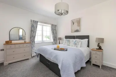 a bedroom with a bed and a mirror and a window at Laundry Cottage: Drumlanrig Castle in Thornhill