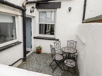 a patio with two chairs and a table and a window at Stanegarth in Keswick