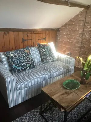 a living room with a couch and a table at Historic converted byre in courtyard of 16C house in Caldbeck