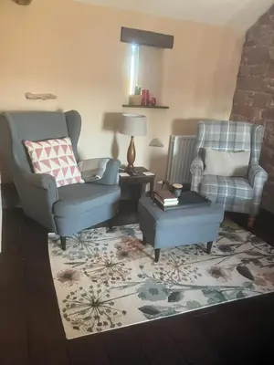 a living room with two chairs and a coffee table at Historic converted byre in courtyard of 16C house in Caldbeck