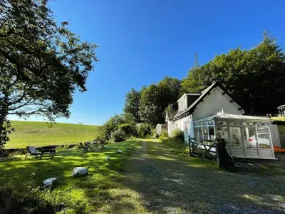 a house with a bench in front of a yard at Bar Hill Lodge in Gatehouse of Fleet