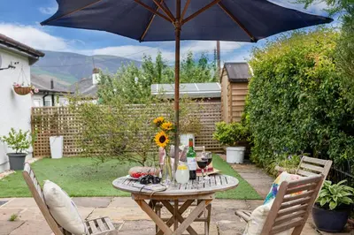 a picnic table with an umbrella in a backyard at Finest Retreats - The Duck House in Braithwaite