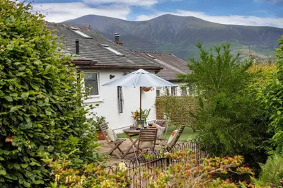 a house with a table and an umbrella in the yard at Finest Retreats - The Duck House in Braithwaite