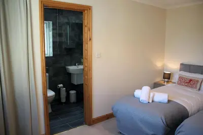 a bedroom with a bed and a bathroom with a sink at Carvetii - Uriah House - 4-Bedroom House sleeps up to 10 people in Belle Vue