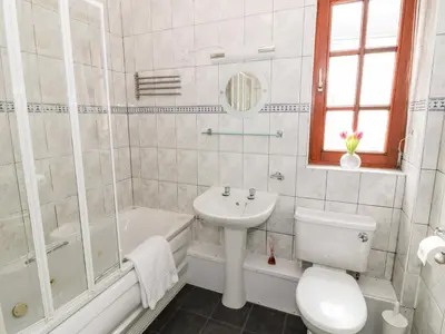 a white bathroom with a sink and a toilet and a tub at Brunston Castle in Girvan