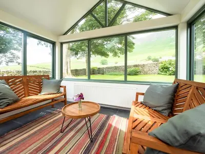 a screened in porch with windows and a table at Wayside Cottage 1637 in Millom