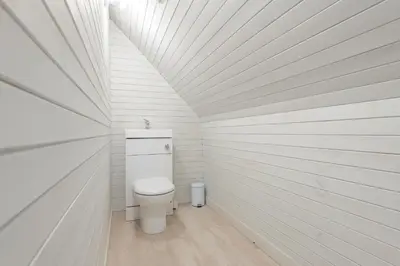 a bathroom with a toilet in a white wall at Nether Newton - Sleeps 12, Hottub, Sauna, Private Garden in Newmilns