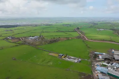 an aerial view of a green field with houses at Alton Villa, Sleeps 12, Great for Families, Undercover Hotub & Games Room in Newmilns