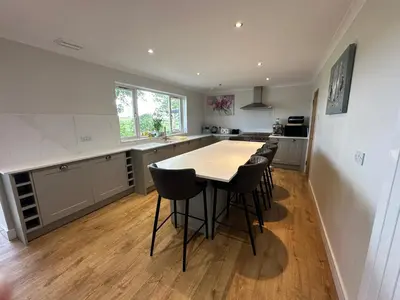 a kitchen with a table and some chairs in it at Alton Villa, Sleeps 12, Great for Families, Undercover Hotub & Games Room in Newmilns