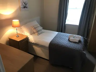a small bedroom with a bed with a lamp and a window at The Maxwell Arms Hotel in Dalbeattie