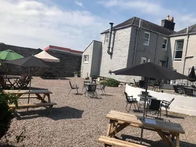 a patio with tables and chairs and umbrellas at The Maxwell Arms Hotel in Dalbeattie
